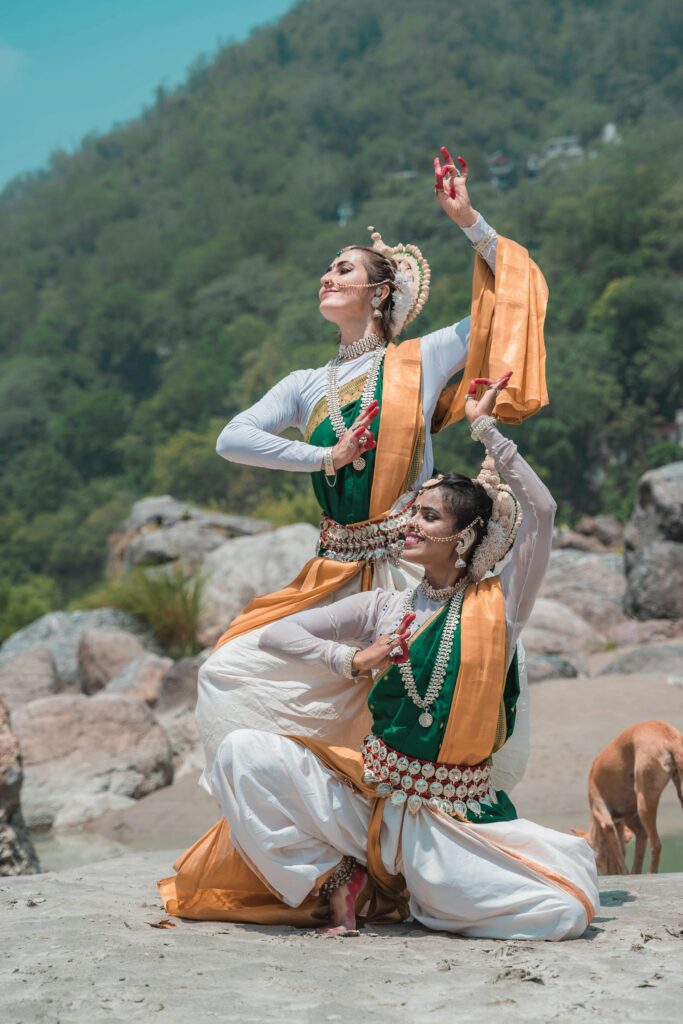 Two women in traditional Indian attire performing an elegant dance on a beach in Puri, India.