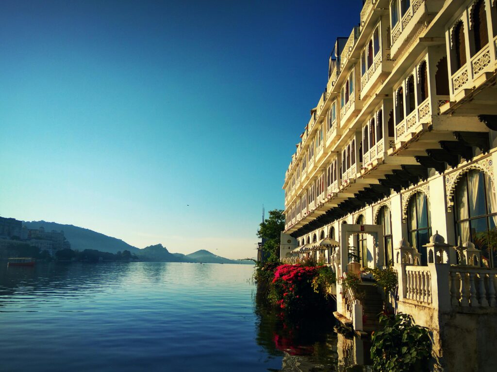 Stunning view of a lakeside palace in Udaipur, reflecting its intricate architecture on the serene water.(Luxury Travel in Rajasthan)