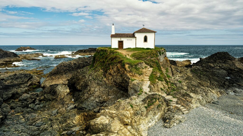 Charming coastal chapel perched on rocky cliffs overlooking the ocean under a cloudy sky( Visit in Rajasthan).