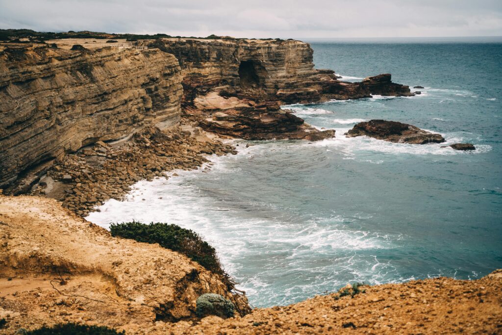 Coastal cliffs and ocean waves in the Faro District, Portugal, showcasing natural beauty.