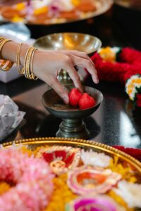 Hand reaching for sweets in a ceremonial setup with vibrant colors and decorations.